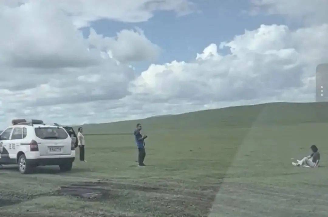 黑N法院警车停草原上一男一女旁边拍照，官方回应：不存在公车私用，工作人员帮一女性游客拍照